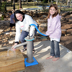 An image of Councillor Teresa Lane trying one of the new water play pumps with Jade Harper, 10, in Eridani Park at Kingston which has undergone a $1.7 million upgrade.