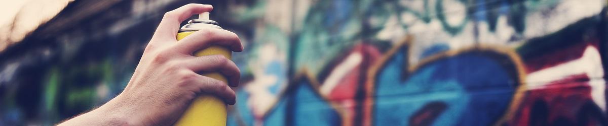 person spray painting graffiti on a brick wall