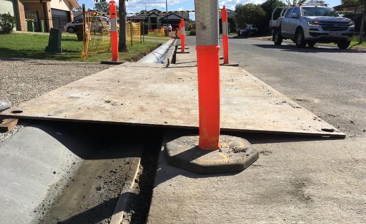 A board placed over the kerb where it has been repaired to allow cars to drive over to access properties