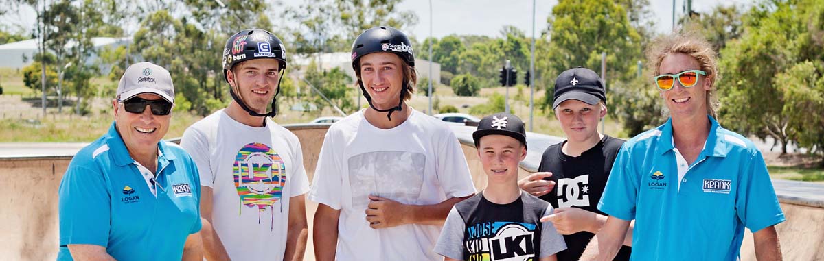 Teenage skaters stand smiling with adults dressed in KRANK branded tshirts