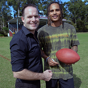 An image of City of Logan Mayor Jon Raven (left) getting an autographed souvenir football from retired NFL star Kenny Still at the Logan City Council-supported NFL Flag trial session at Marsden State High School today.