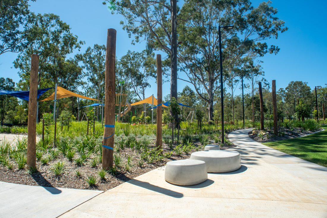 Picture of the pathway going through Pebblecreek parkland showing shade sails, decorative concrete seating and landscaping