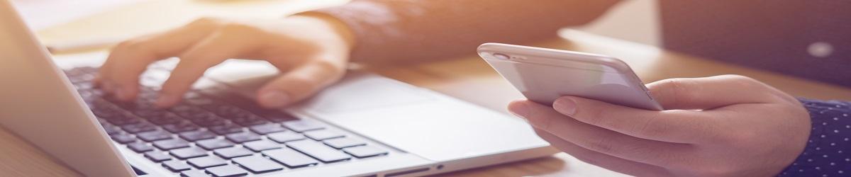 Picture of person typing on computer and phone submitting feedback