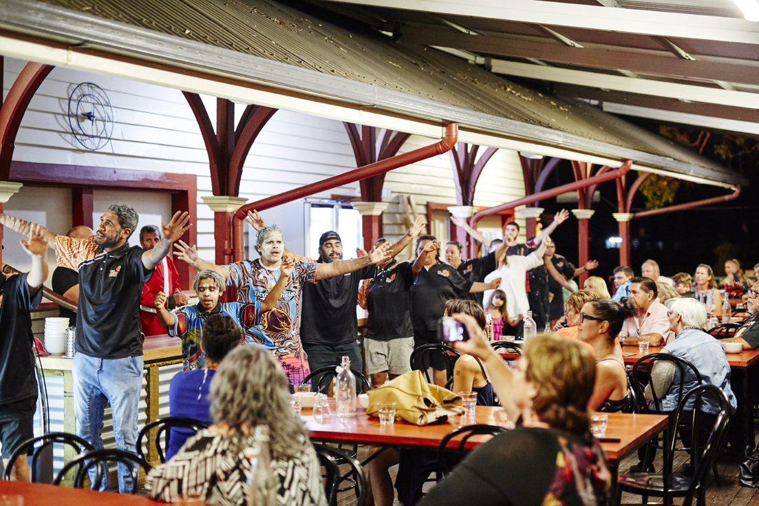 Picture of people sitting around tables watching indigenous dancing at the NAIDOC Wild Foods and Cultural Festival 