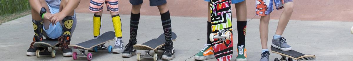 Picture of 5 boys sitting and standing on their skateboards with colourful shoes and socks