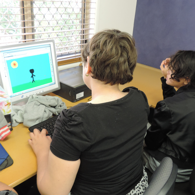 A boy and a girl looking at a computer screen sitting at a desk