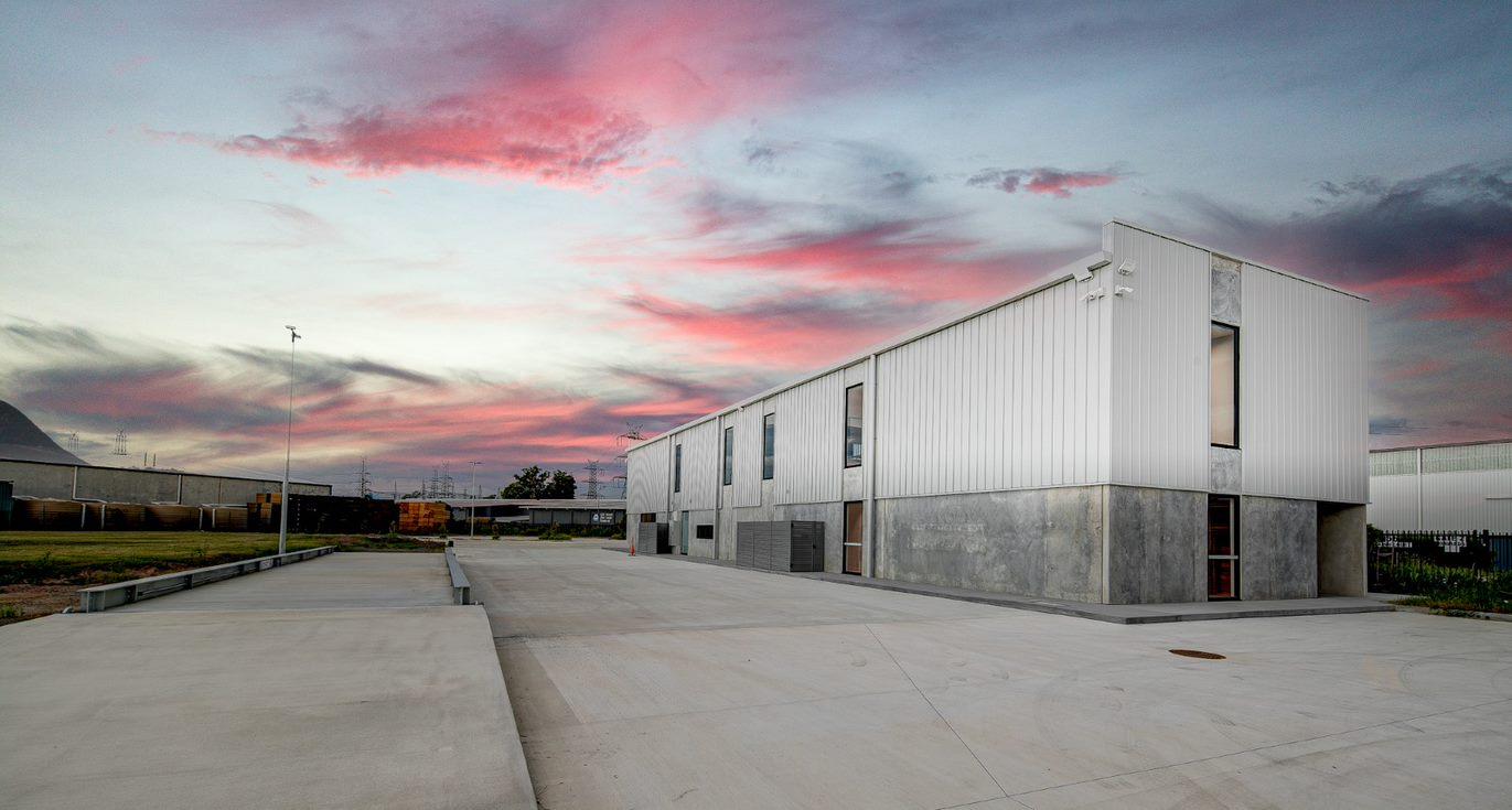 Picture of the V Resource building and surrounding concreted areas with a sunset pink sky in the background