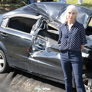 Woman stands in front of crashed car