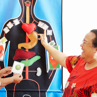 A woman pointing to the heart on a human anatomy poster